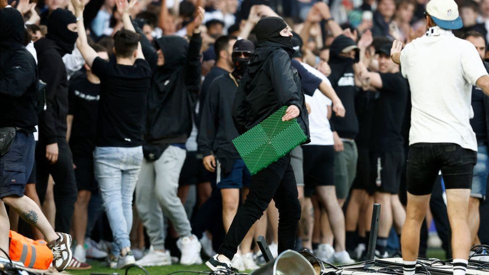 Fans - some covering their faces - on the pitch after Saturday's violence