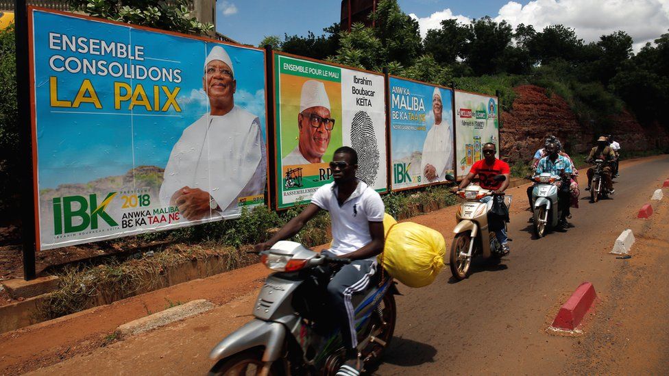 People ride their motorcycle past electoral billboards of Ibrahim Boubacar Keita, the Malian president