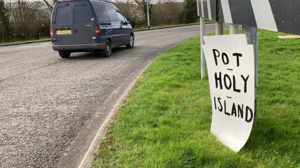 'Pot Holy Island' sign on a grass traffic island