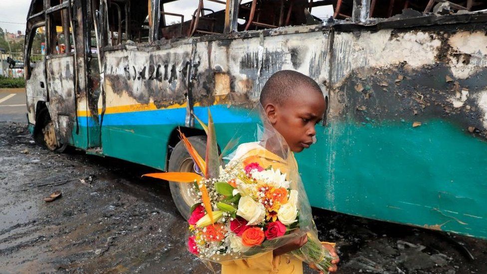 A boy carries a bouquet of flowers as he walks past a bus torched by unknown people ahead of protests by supporters of Kenya's opposition in Nairobi, Kenya - Tuesday 2 May 2023