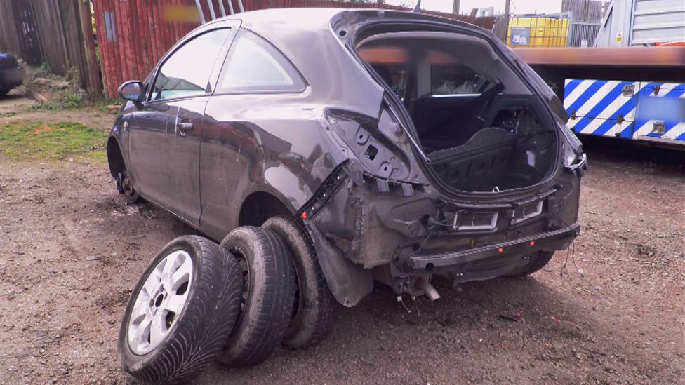 Wrecked Vauxhall car with boot door and tires removed