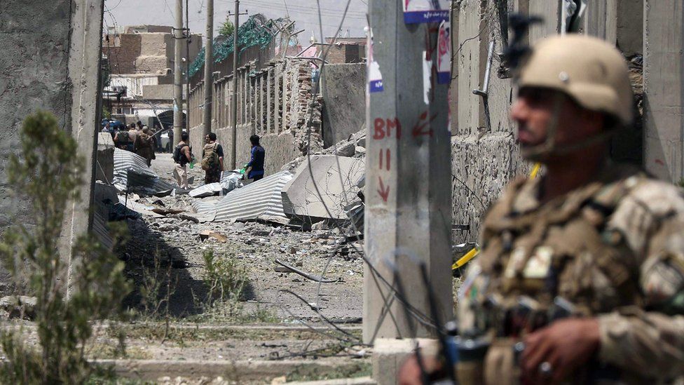 An armed Afghan security officer stands guard at the site of a bomb blast in Kabul on 7 August 2019