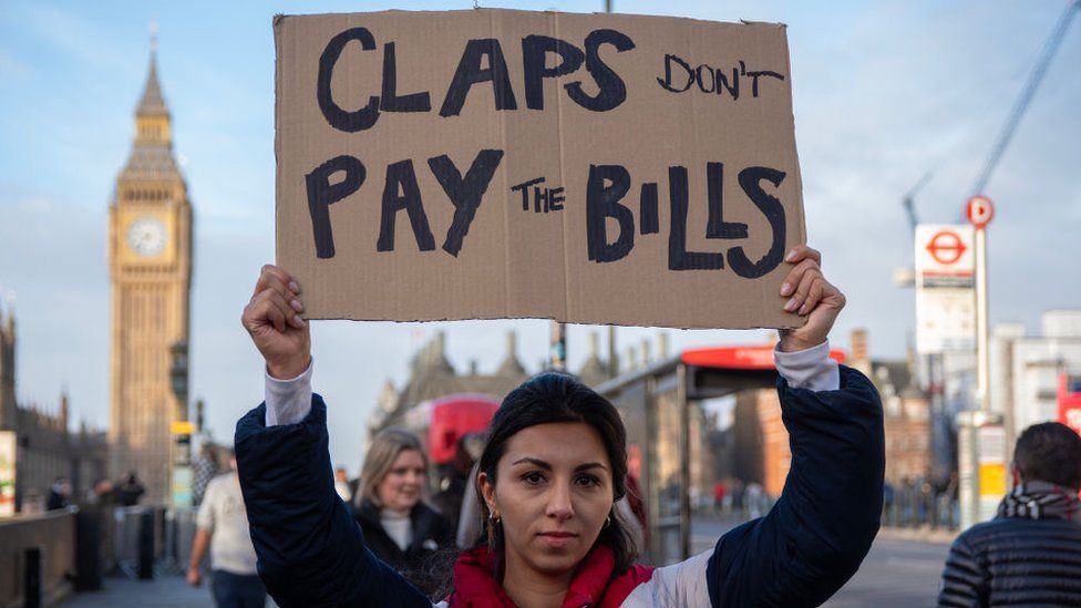 LONDON, UNITED KINGDOM - 2024/01/03: A protester holds a placard reading "Claps don't pay the bills" during a demonstration outside of the St Thomas Hospital in London. Big Ben is seen at the distance. Junior doctors set the longest strike at the history of the NHS (National Health Service). According to the BMA (British Medical Association) the junior doctors are on strike because the value of their salaries has been reduced by more than a quarter since 2008/9. (Photo by Krisztian Elek/SOPA Images/LightRocket via Getty Images)