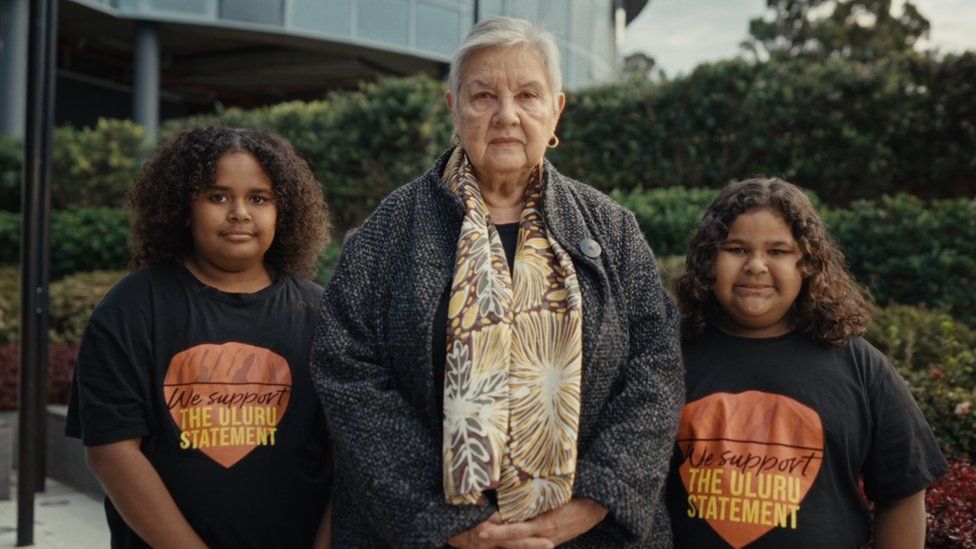 Сопредседатель Uluru Dialogue Пэт Андерсон (в центре) с двумя девушками в рубашках Uluru Statement