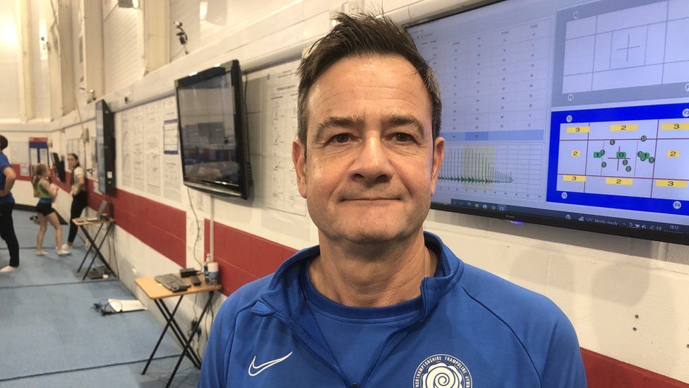 Man with short dark hair wearing a blue tracksuit