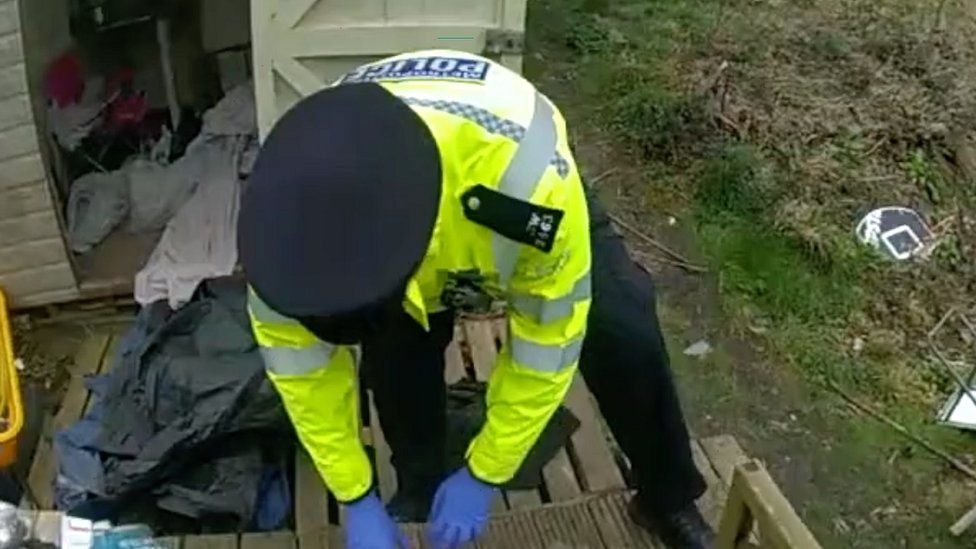 A police officer searching through the bag where baby Victoria was discovered