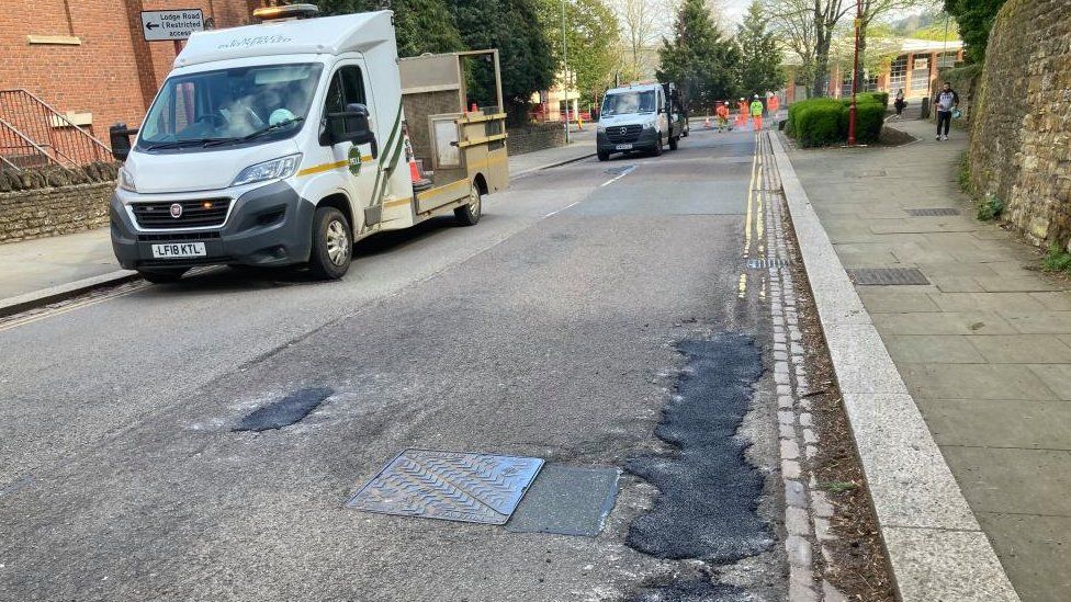 Black patches show where holes have been filled on a road