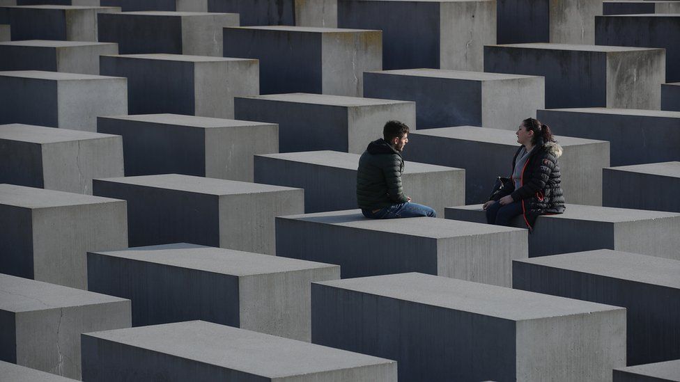 Visitors sit while visiting the Holocaust memorial in Berlin