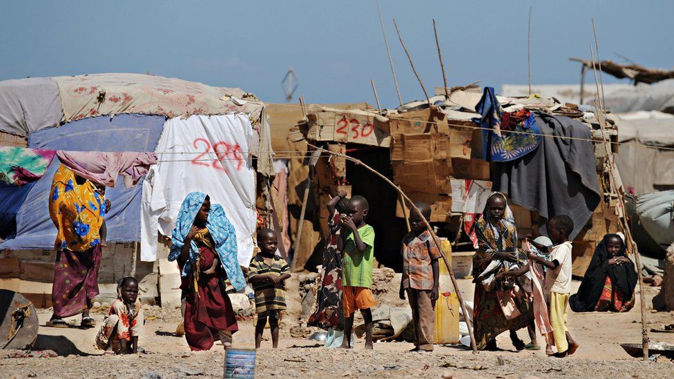 Women and children stand in front of their makeshift shelters at a camp for Internally Displaced People in Bossaso, a town in the northern breakaway state of Puntland, on 20 October 2009.