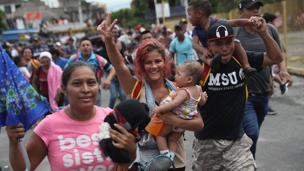 Families in the migrant caravan celebrate after forcing open a gate at the Guatemala-Mexico border