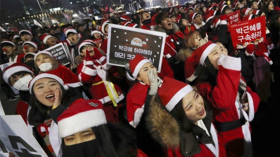 People wearing Santa Claus costumes shout during a rally calling for South Korean President Park Geun-hye to step down in Seoul, South Korea, on 24 December, 2016.