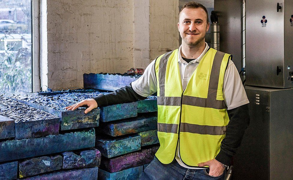 Ein Mitarbeiter der Thermal Compaction Group steht vor seinen Blöcken aus recyceltem Kunststoff