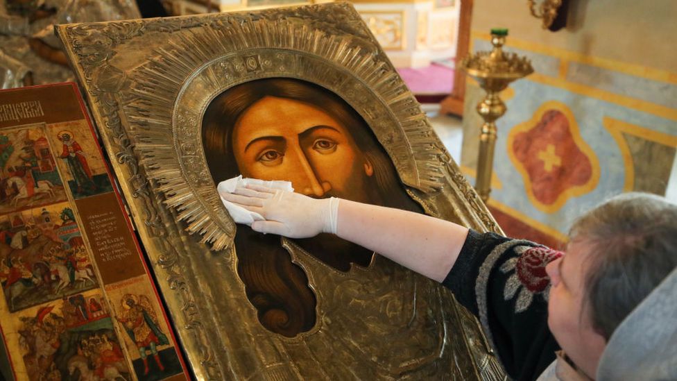 A believer sanitises an icon case in the Church of St Alexius, Moscow, March 2020