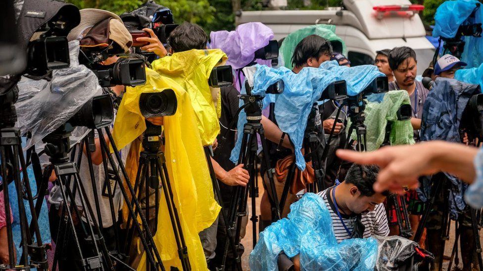 Dozens of media cameras are pictured, covered with makeshift waterproof protection