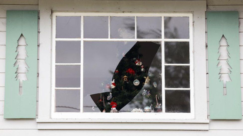 A Christmas tree seen through broke windows
