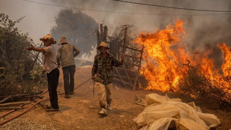Men walking next to a raging fire