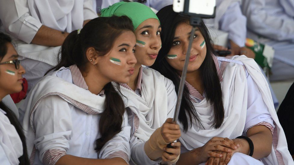 Young Pakistani women using a selfie-stick at a cricket match, 2015