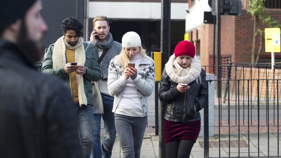 People crossing the road looking at mobile phones