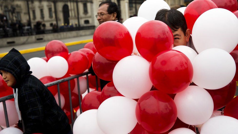 A supporter of Peru's new president hides in balloons