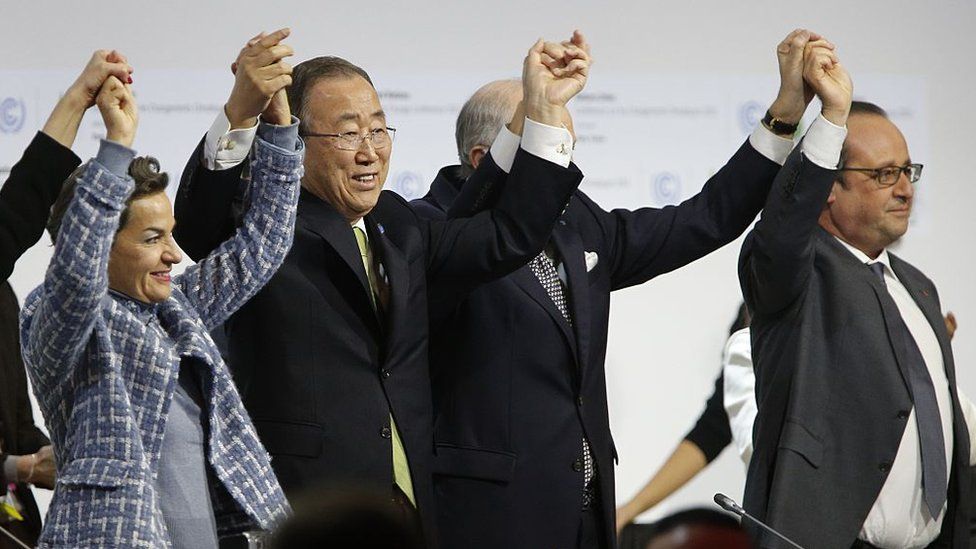 Christiana Figueres, Ban Ki Moon, F Laurent Fabius, and France's President Francois Hollande raise hands after adoption of a global warming pact at the COP21 Climate Conference