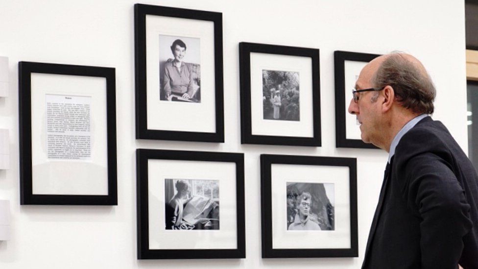 Man looking at Philip Larkin's photographs on a wall