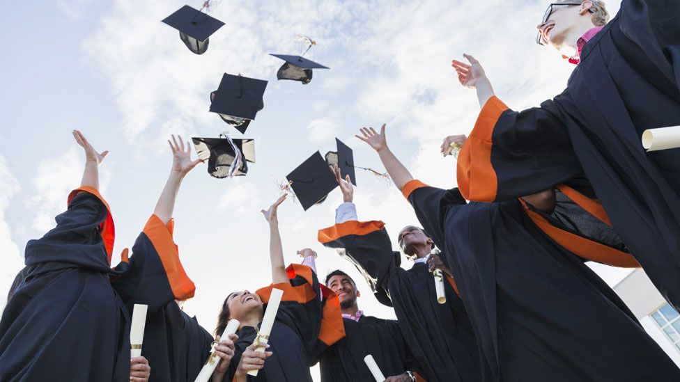 Stock picture of university graduates throwing mortar boards in the air