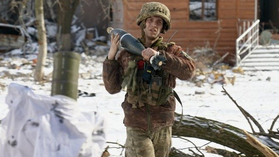 A soldier carrying a mortar shell in Vuhledar