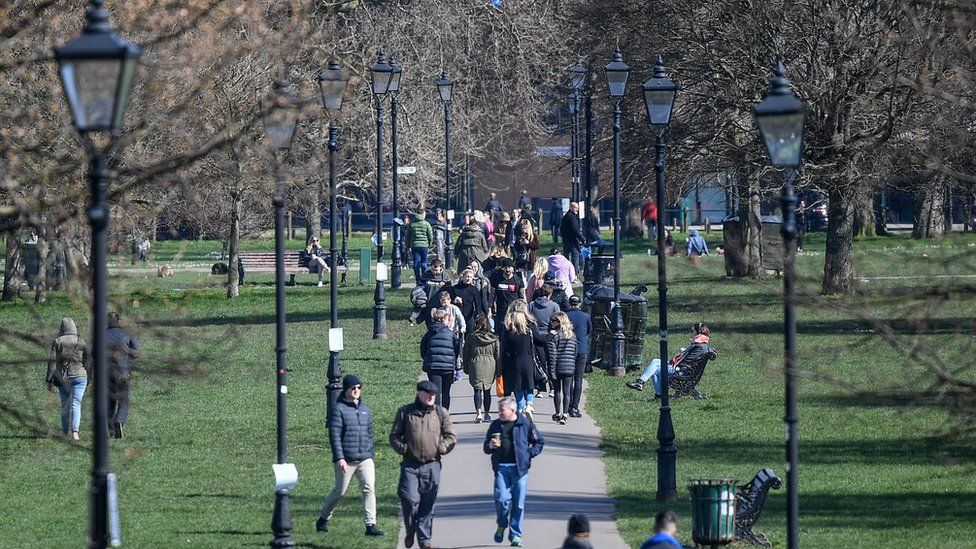 People are seen walking on Clapham Common on March 22, 2020 in London, United Kingdom.