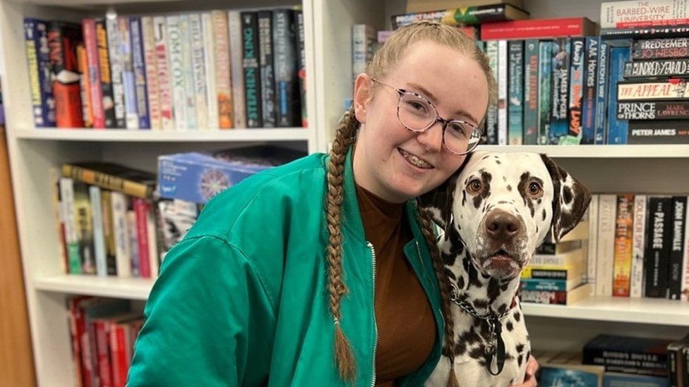 Teenager girl and dalmatian dog in library