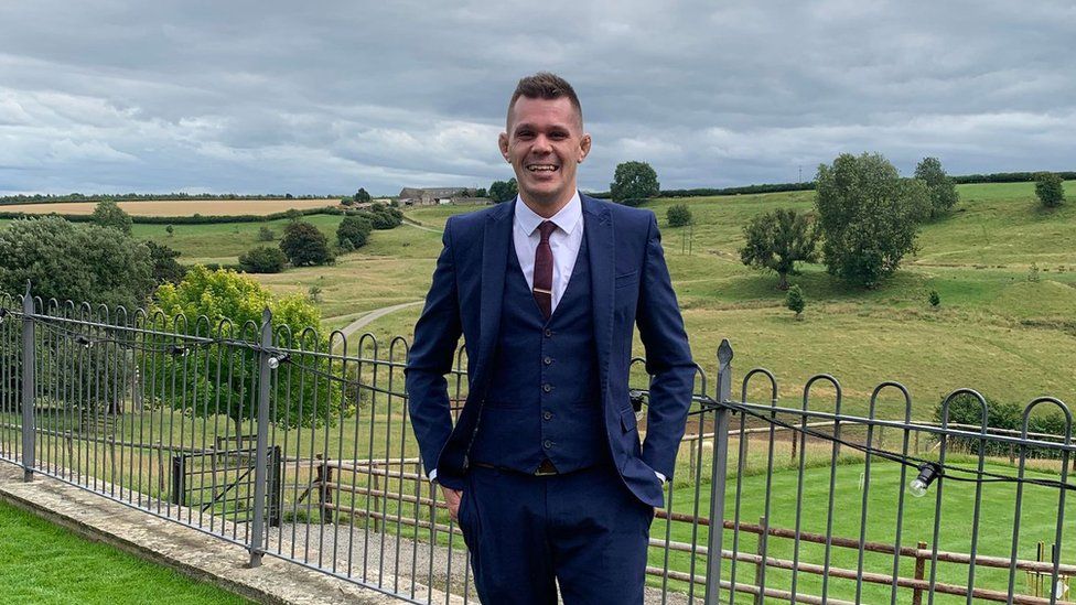 Andrew Whitehead in a suit standing in a field