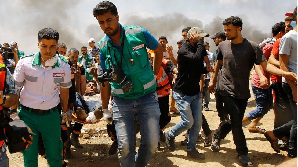 Emergency services and Palestinians carry a wounded protestor during clashes with Israeli security forces near the border between Israel and the Gaza Strip, east of Jabalia on May 14, 2018