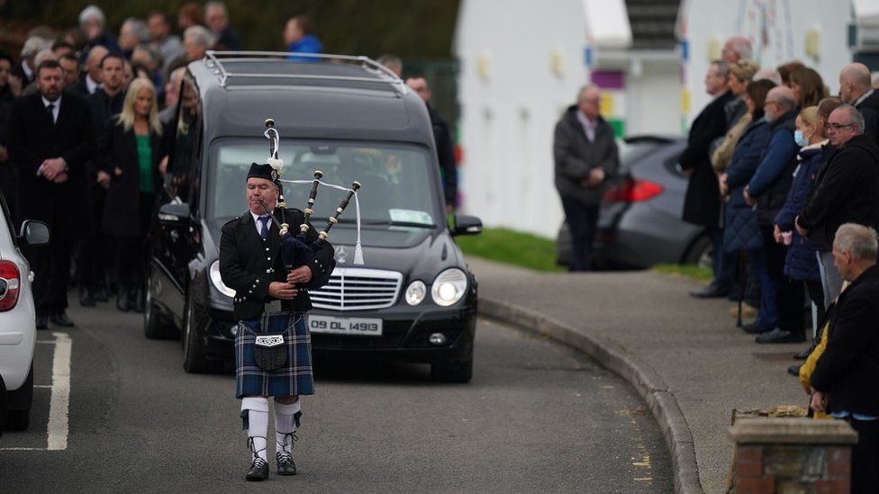 A piper plays as the hearse carrying Mr McGill, arrives at St Michael's Church for his funeral Mass