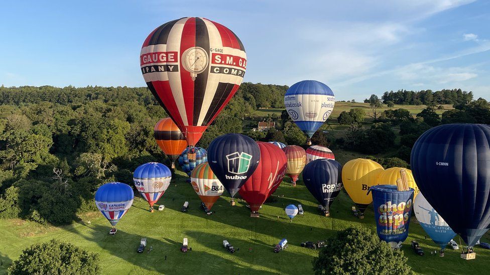 Around 18 hot-air balloons rising from the ground on Ashton Court Estate