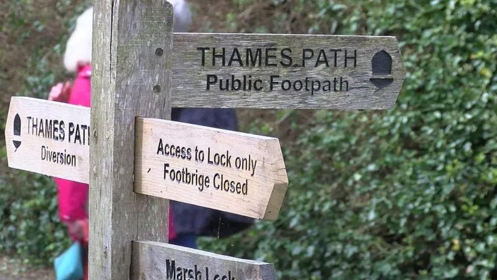 A wooden sign indicating 'Thames Path Diversion' to the left, and 'Access to lock only, Footpath closed' to the right