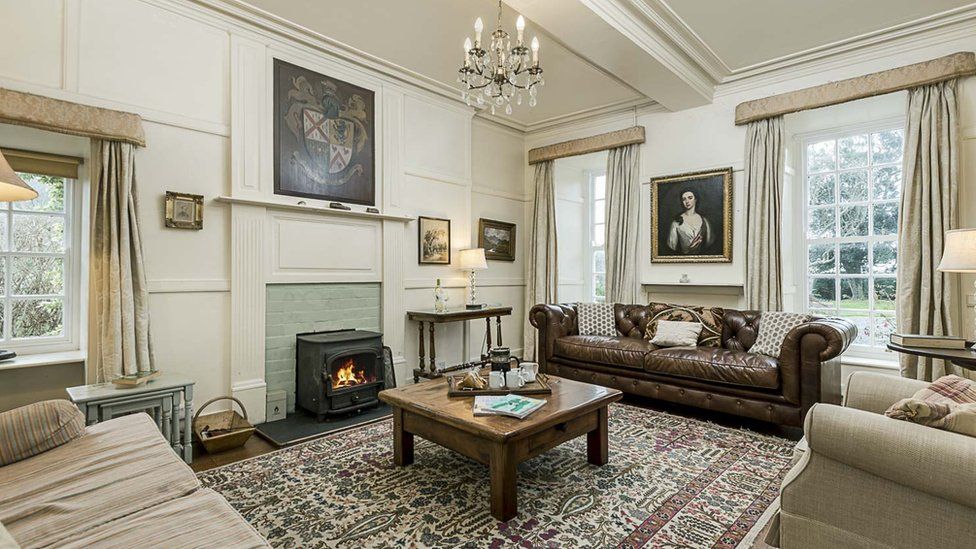 Inside a sumptuous lounge in the manor house, displaying family coat of arms on the wall