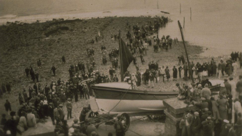 Old image of the Overland Launch. The Louisa can be seen at the shore, with lots of people nearby.