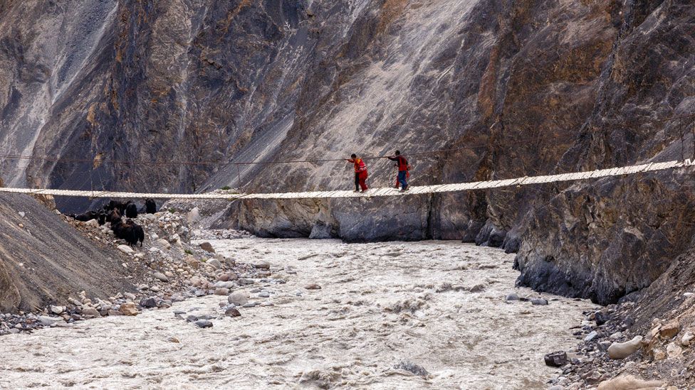 A rope bridge suspended across a mountain river