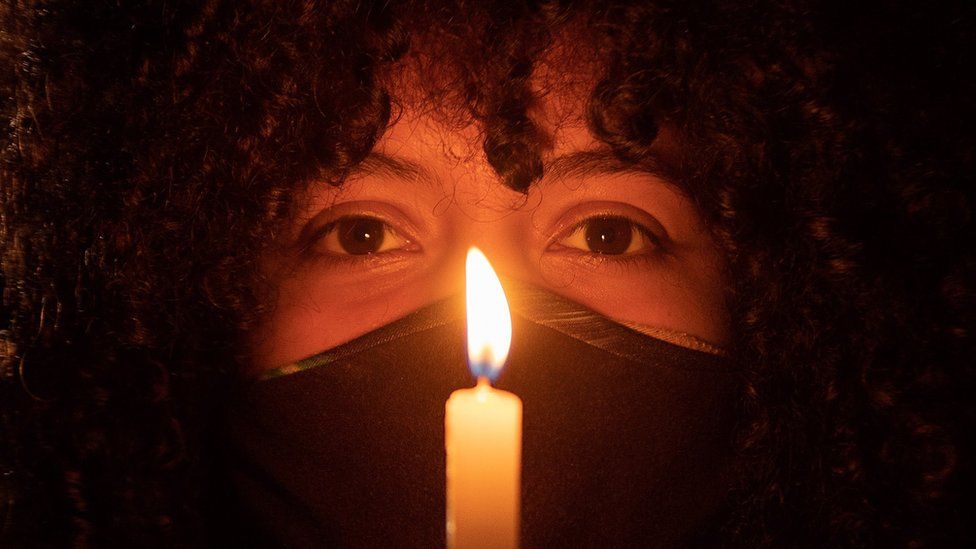 Женщина держит свечу во время акции протеста в Бразилиа