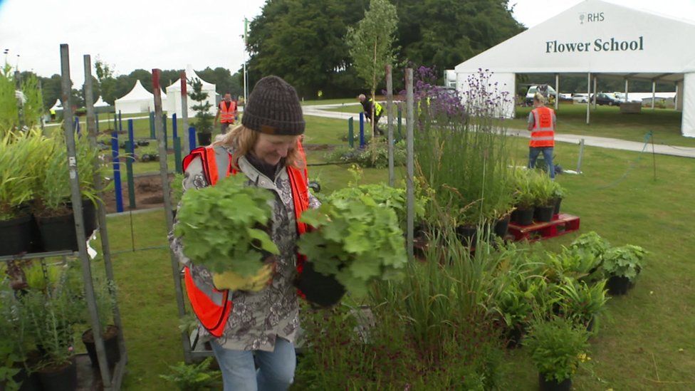 Woman carrying plants outside Flower School tent