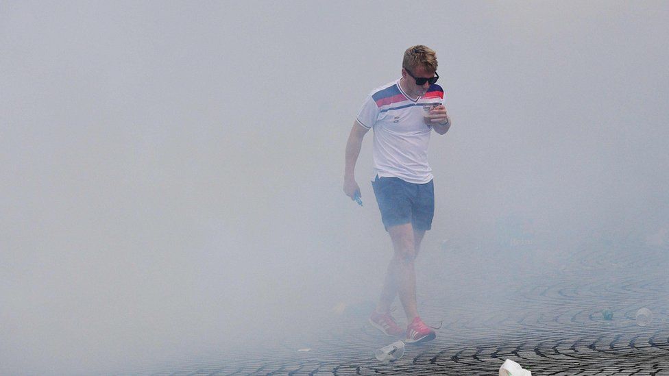 An England fan walks through tear gas in Marseille