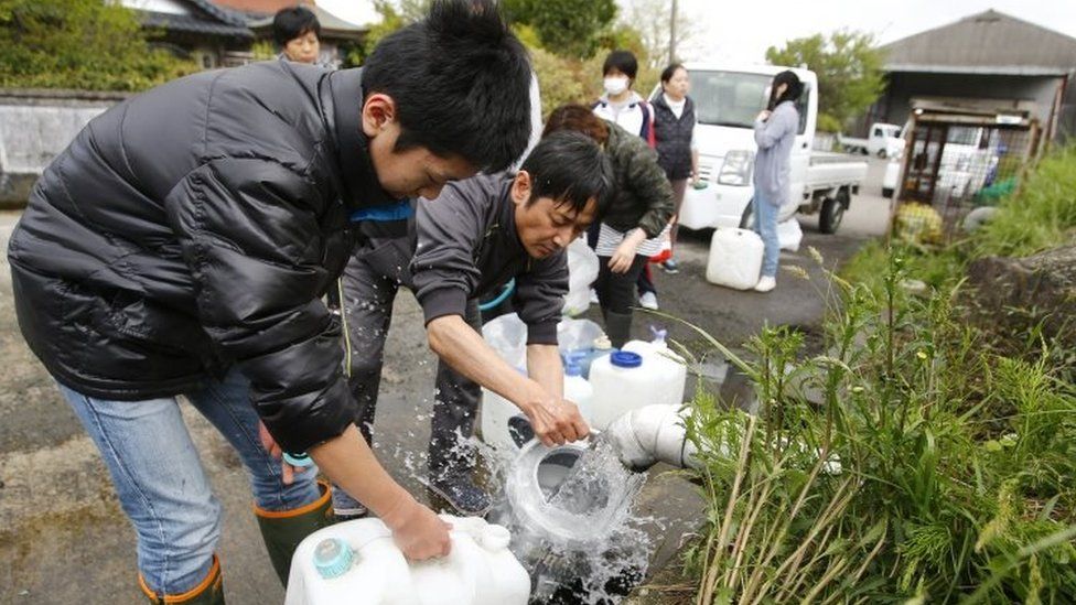 Evacuees collect spring water in plastic containers in Aso, Kumamoto prefecture, Japan (17 April 2016)