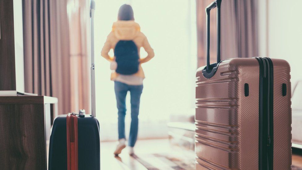 Woman who has just entered hotel room with suitcases