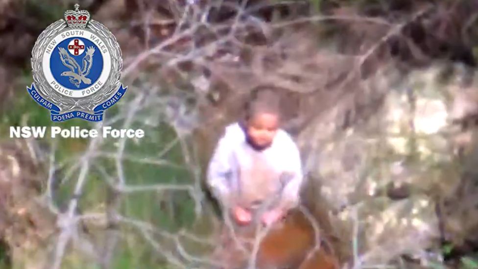 Aerial shot from police helicopter of AJ kneeling in a riverbed