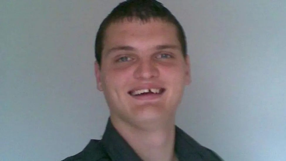 Photograph of Kyle Marshall wearing black shirt and smiling