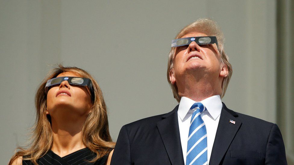 Donald and Melania Trump look upwards in their eclipse glasses