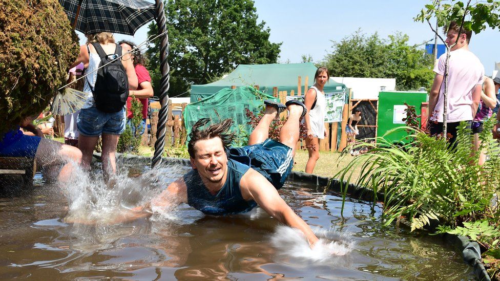 A festival-goer jumps into a water feature to cool down on the Saturday of Glastonbury Festival at Worthy Farm
