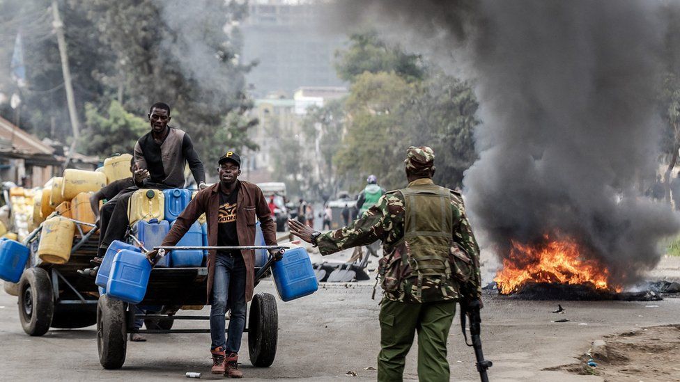 A Kenya Police officer stops some workers at a closed road during demonstrations in Nairobi, Kenya on July 12, 2023