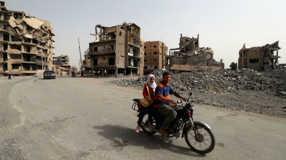 A couple on a moped amid the ruins of the Syrian city of Raqqa in October 2018