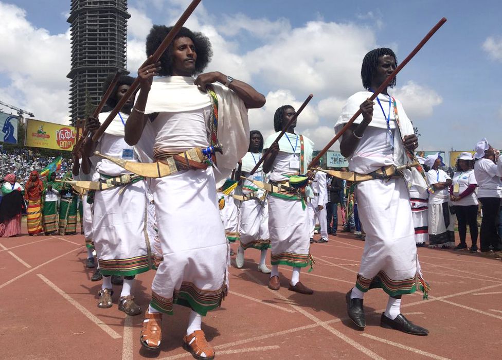 Men dancing carrying sticks