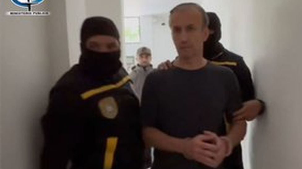 Tarek El Aissami shown being led away in handcuffs in a photo released by the Ministry of Communication